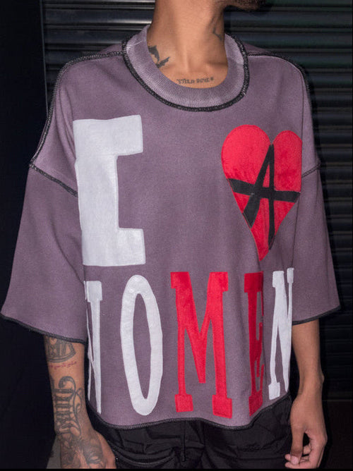 Person wearing a oversized t-shirt with large text and a red heart design.
